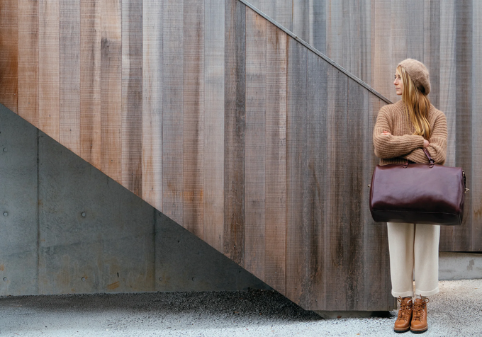 Woman holding a purple bag against a modern architectural background